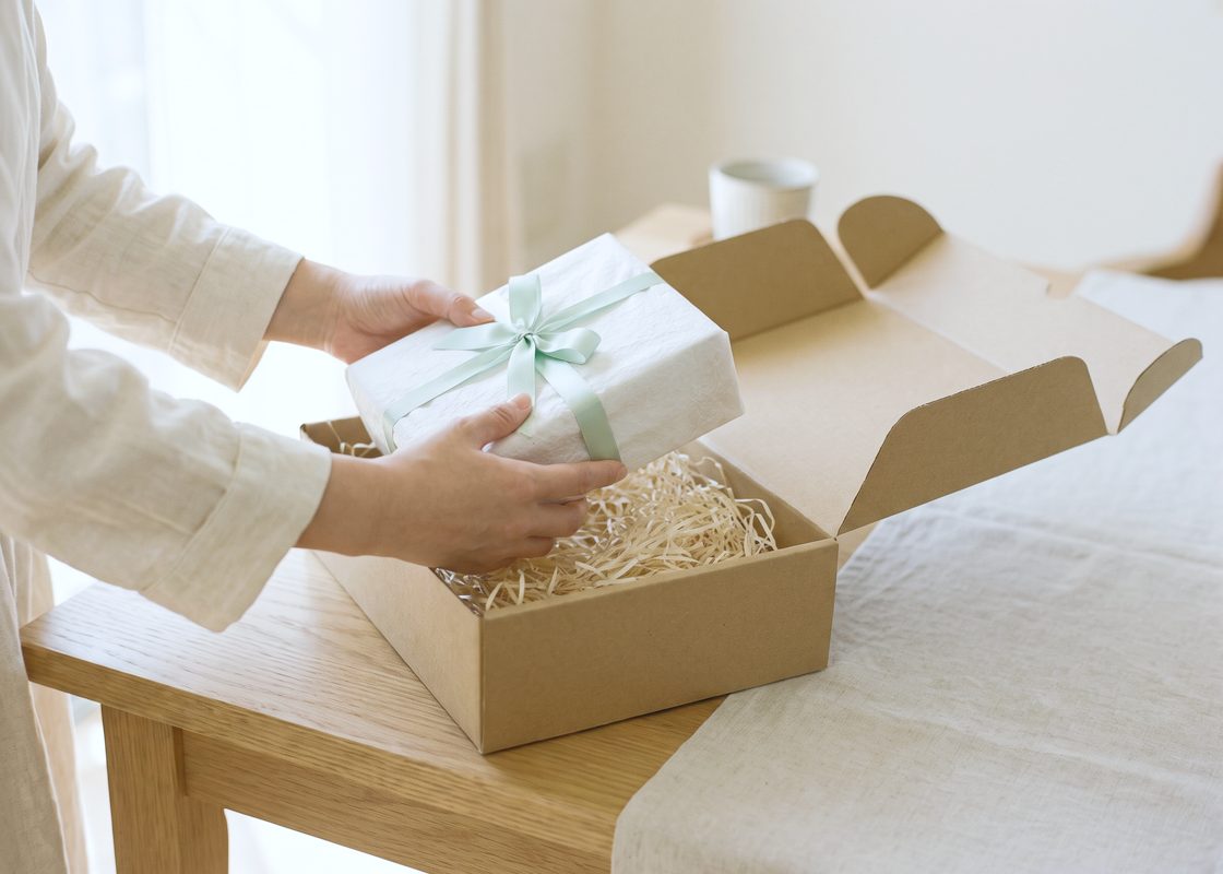 届いた箱から、リボンをかけた包みを取り出す手元